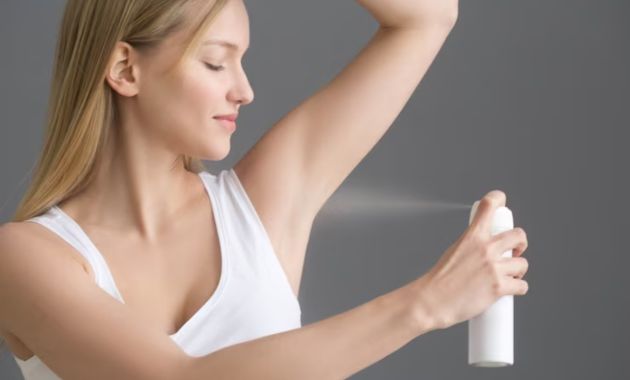 a woman applying deodrant to her armpit to minimize body odour