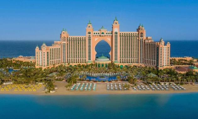 a large building with a pool and a beach with Atlantis, The Palm in the background