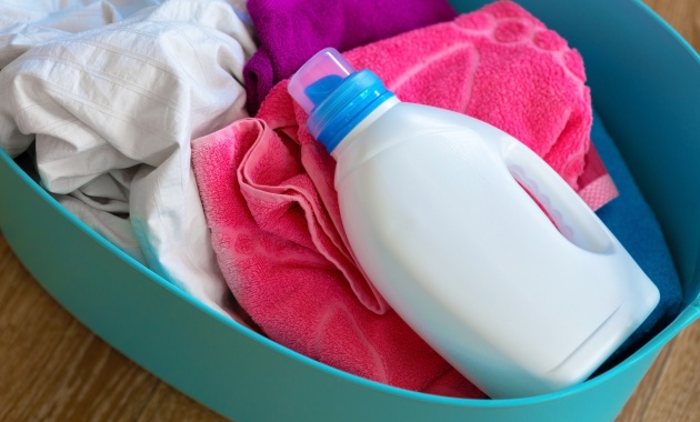 a plastic fabric softener bottle laying over a dark pink color towel 