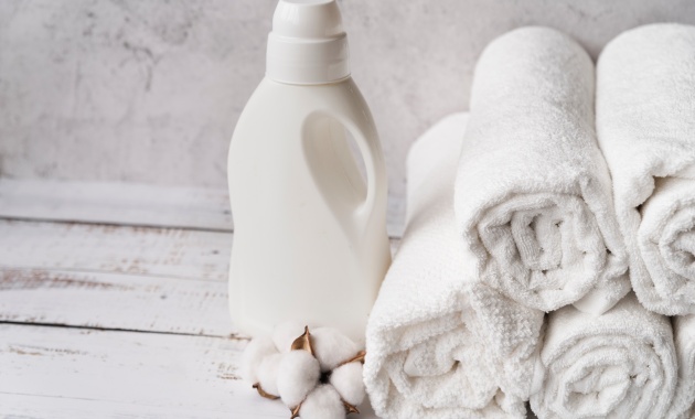 white plastic bottle of fabric softener along with 4 white towels 