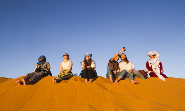 3 girls and 3 boys are enjoying in desert safari dubai, also two of them is bussy in taking selfie together while others are enjoying the view