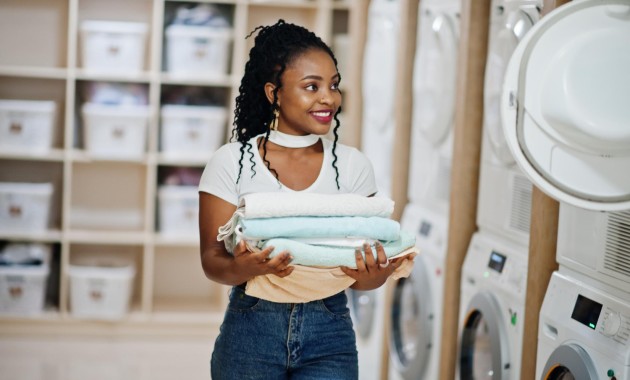 a woman is standing in laundry shop and she is holding 4 towels on her hands 