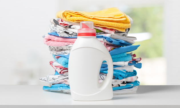 a stack of clothes and a bottle of liquid detergent