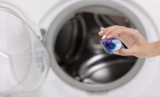 a hand holding a capsule of laundry detergent