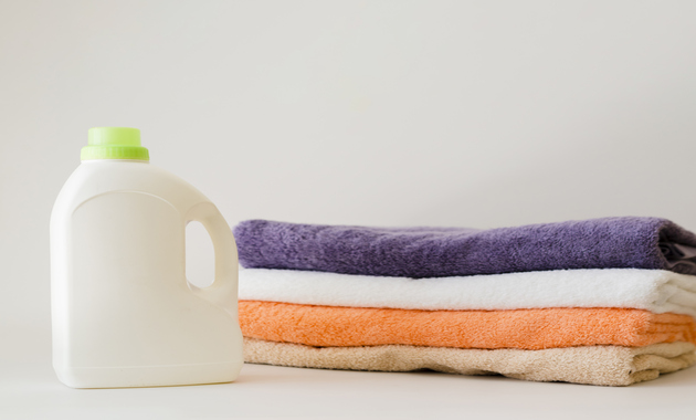 a bottle of fabric softener along with 4 towels placed beside the bottle.