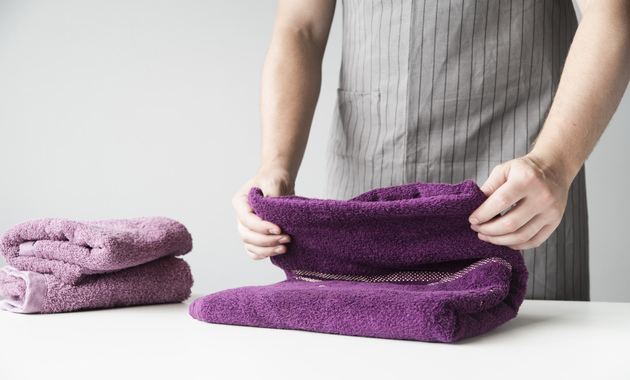 a man is folding a purple color towel 