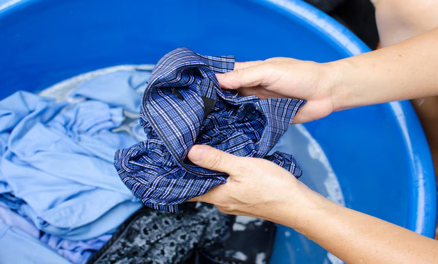 a girl is washing a blur formal check shirt with her hands