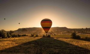 a hot air balloon on a lush green ground with beautiful sunset