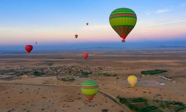 multiple hot air balloons in the air with deserty background and blue sky