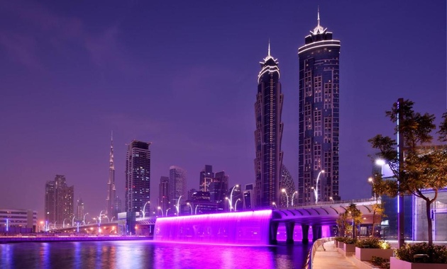 a water fountain with a purple light in the middle of a city