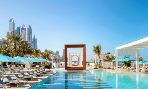 a pool with chairs and umbrellas in front of a city