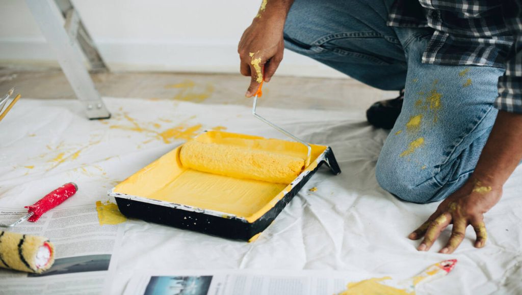 a person painting a tray with yellow paint