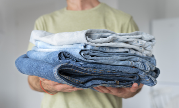 a man holding 3 jeans in his hands