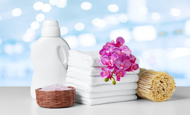 a bottle of fabric softener on a table with stack of towel