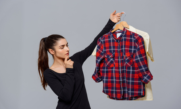 a girl is holding shirts on a hanger