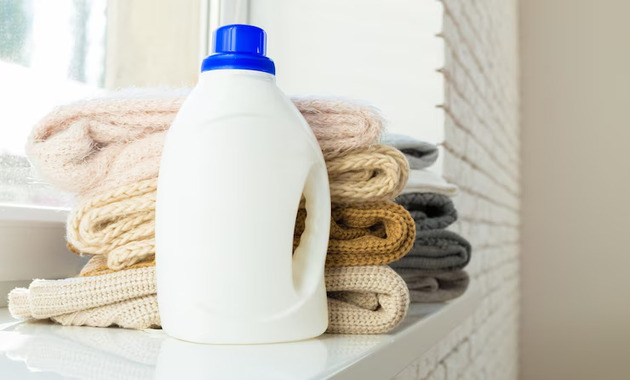 A bottle of detergent placed on a rack with clothes behind