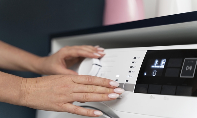 a woman is adjusting the water temperature of the washing machine