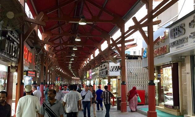 a group of people walking in a covered area of gold souk bazar