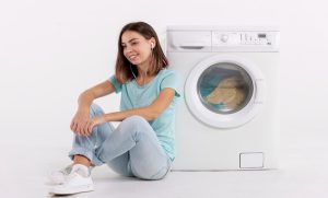 a girl is sitting next to washing machine with white background