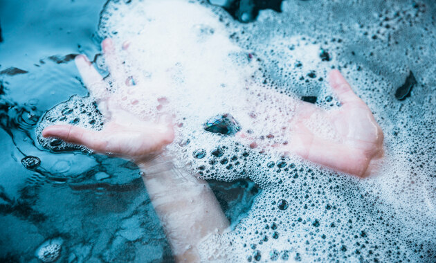 a man is putting his hands on soapy cold water that is prpared for removing soffee stains