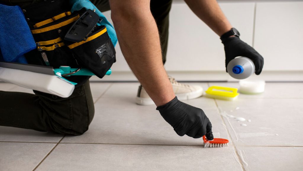 a man is cleaning floor tiles with a brush and cleaning liquid