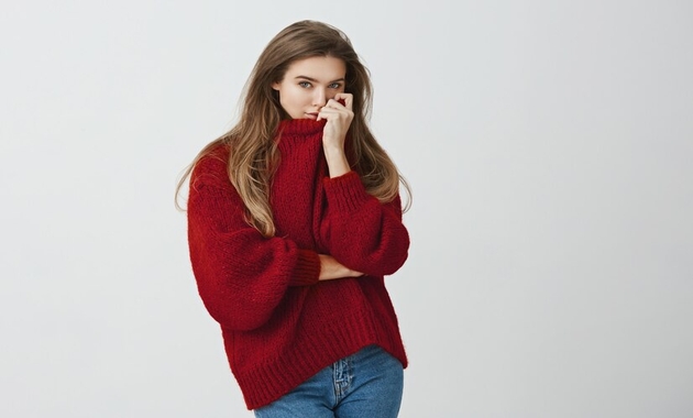 a girl is smelling her maroon sweater