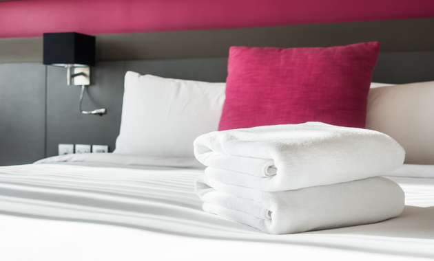 image of a bed with white towels and pink cushions