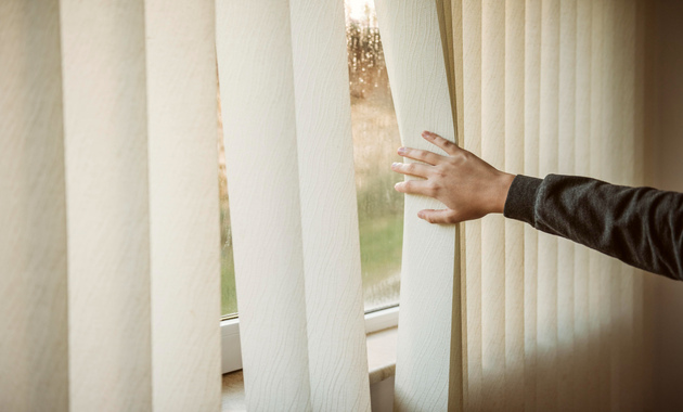 a man is holding the bedroom blinds