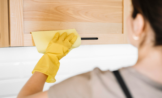 a women is cleaning kitchen cabinets
