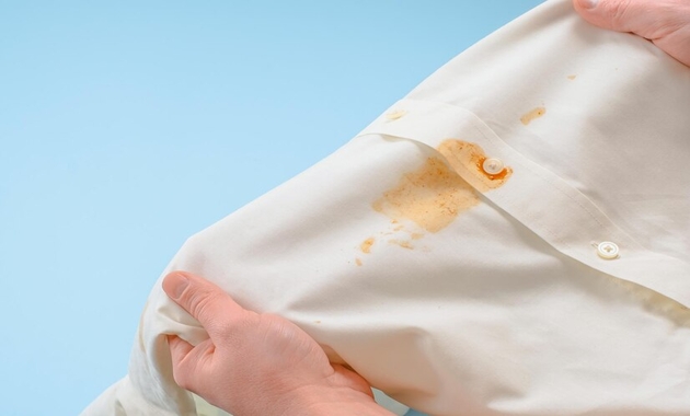 a woman holding a white shirt with stain on it