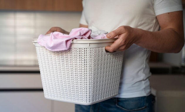 a man is holding a basket full of clothes