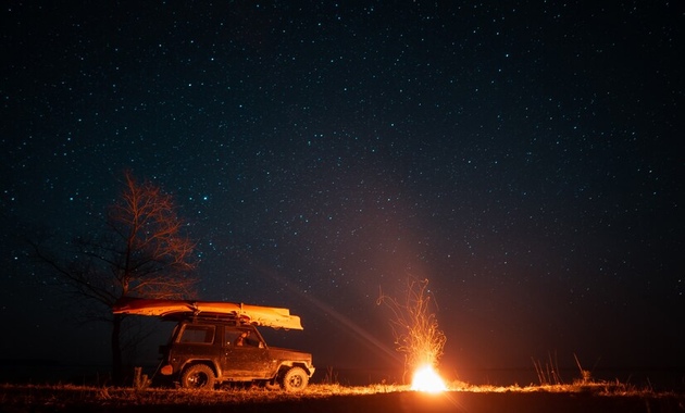 night view of desert with a car and a bonfire