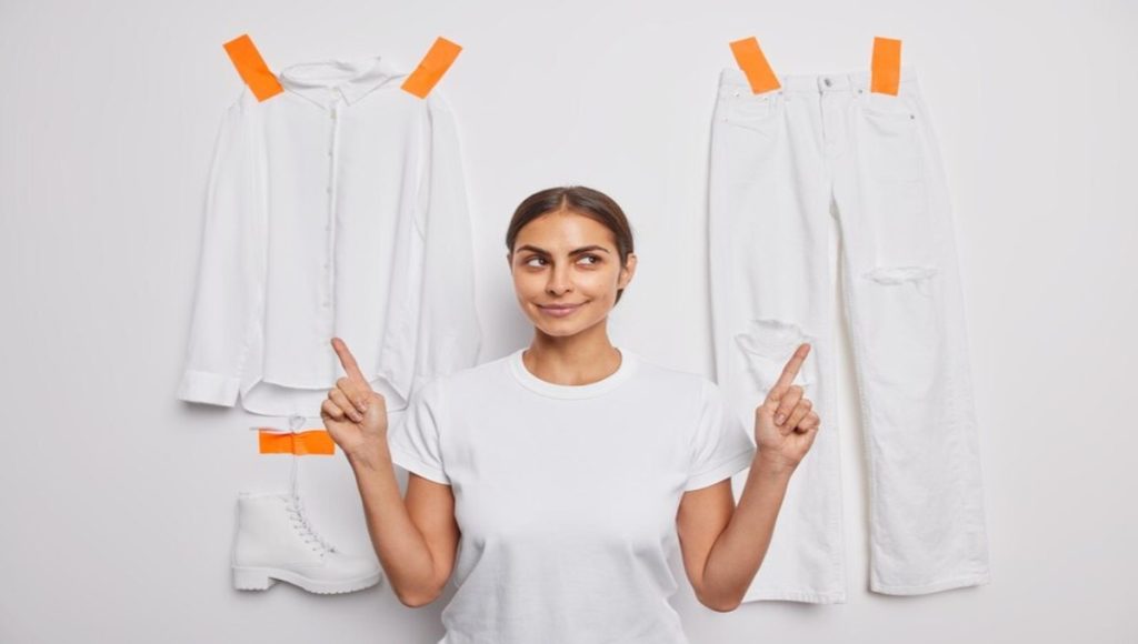 few clothes are pasted on a wall and a woman is pointing towards it and representing laundry stripping