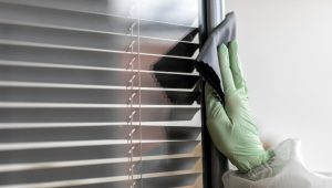 a person cleaning blinds with a cloth