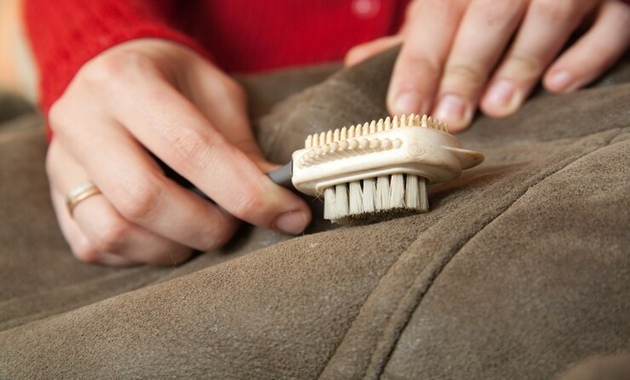 a woman is using a brush to clean leather purse